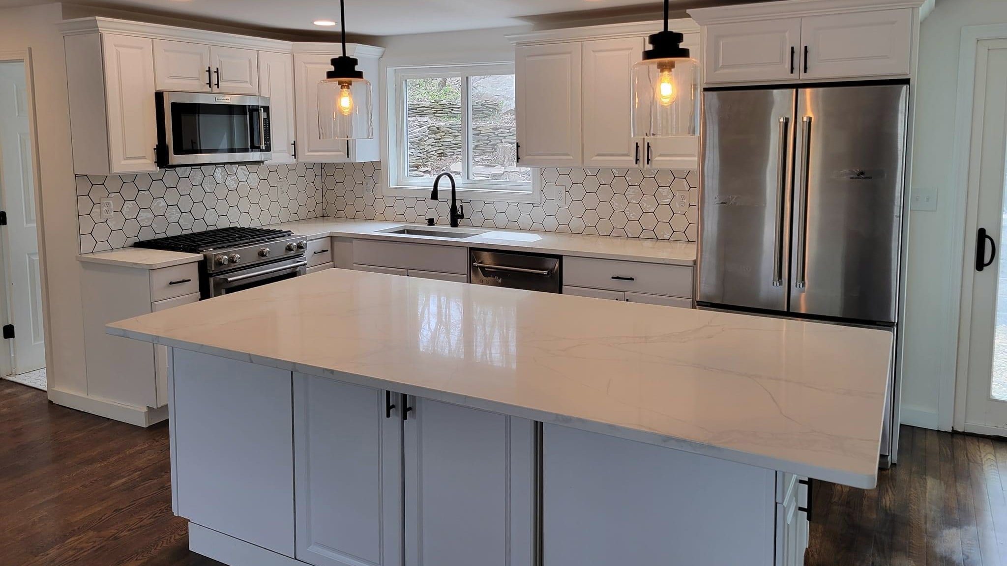 Remodeled white kitchen with a blue island and bar seating, a Brightwork project