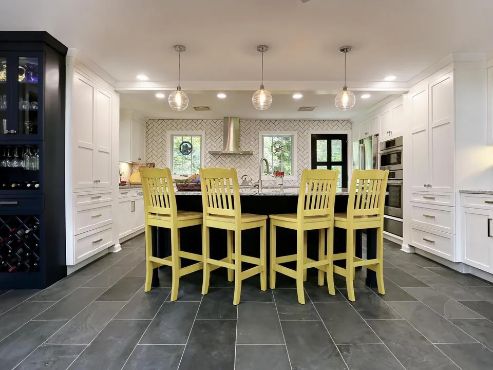 Kitchen island with yellow stools and a herringbone backsplash