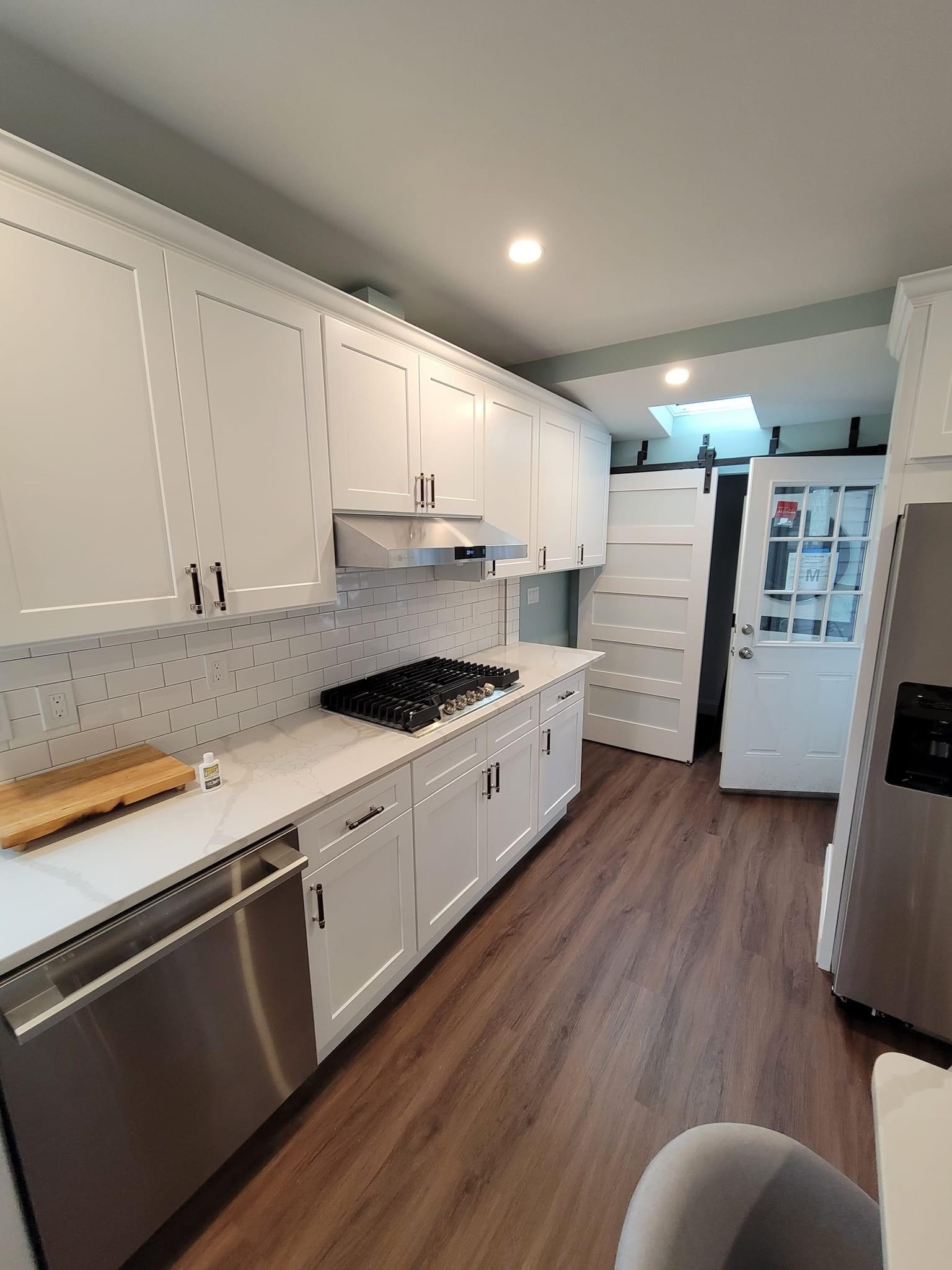 Kitchen appliance wall with gas cooktop, subway-tile backsplash and a barn door beyond, North Reading