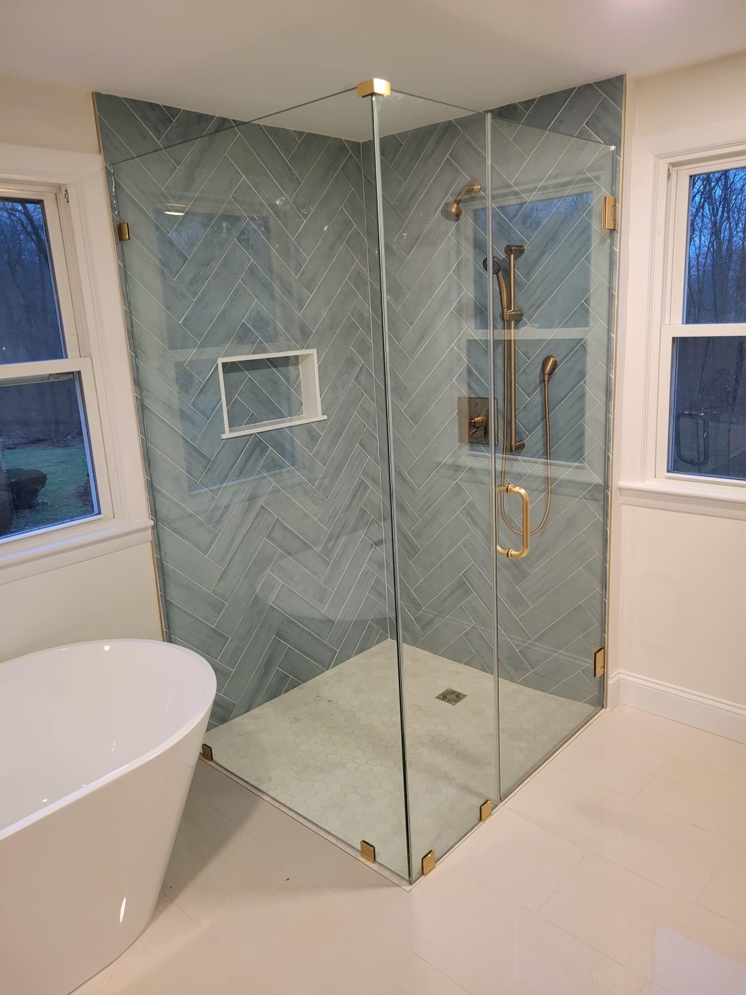 Gray herringbone-tile shower corner with gold fixtures, Middleton