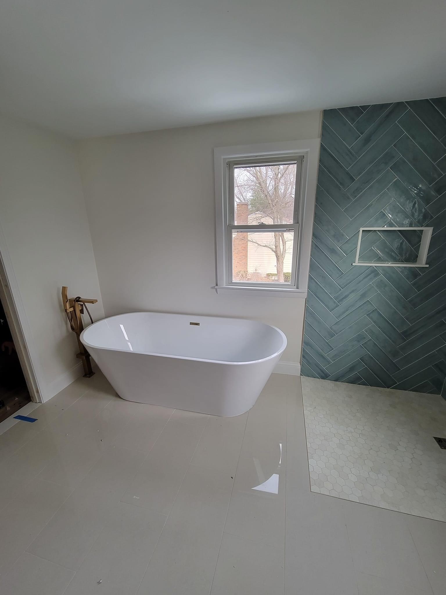 Wide view of the herringbone-tile bathroom with a freestanding oval tub and gold floor-mount filler, Middleton