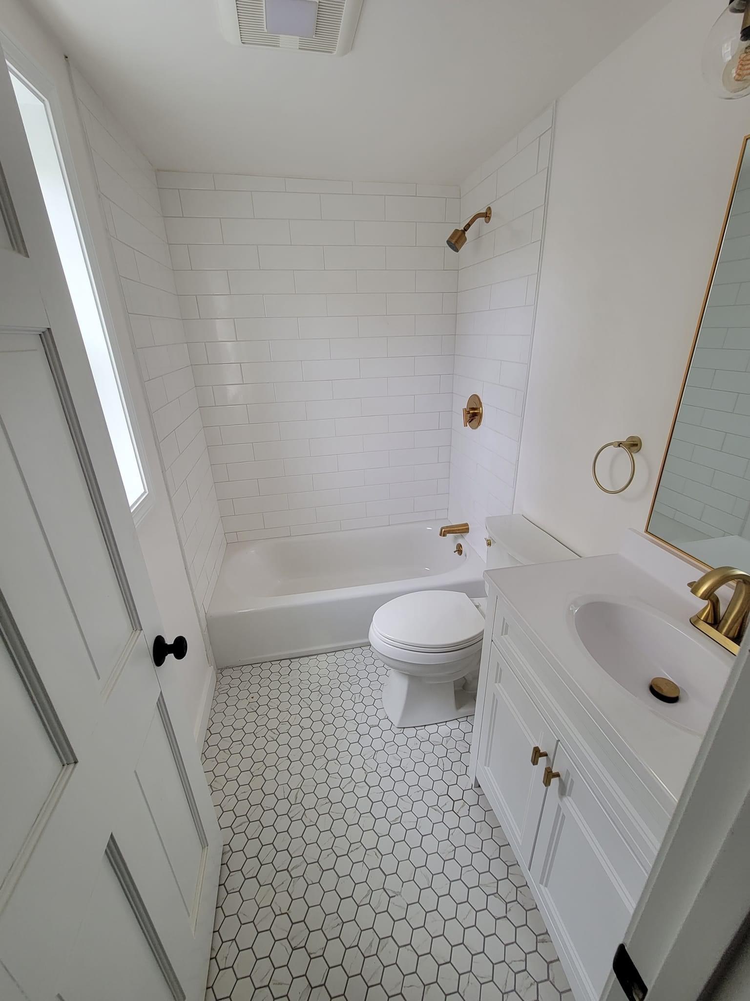A bathroom with white subway tile, gold fixtures and a small vanity, Boxford
