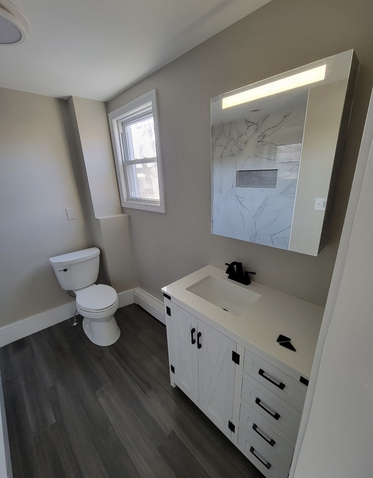 A bathroom with a white shiplap-style vanity and black hardware, Woburn