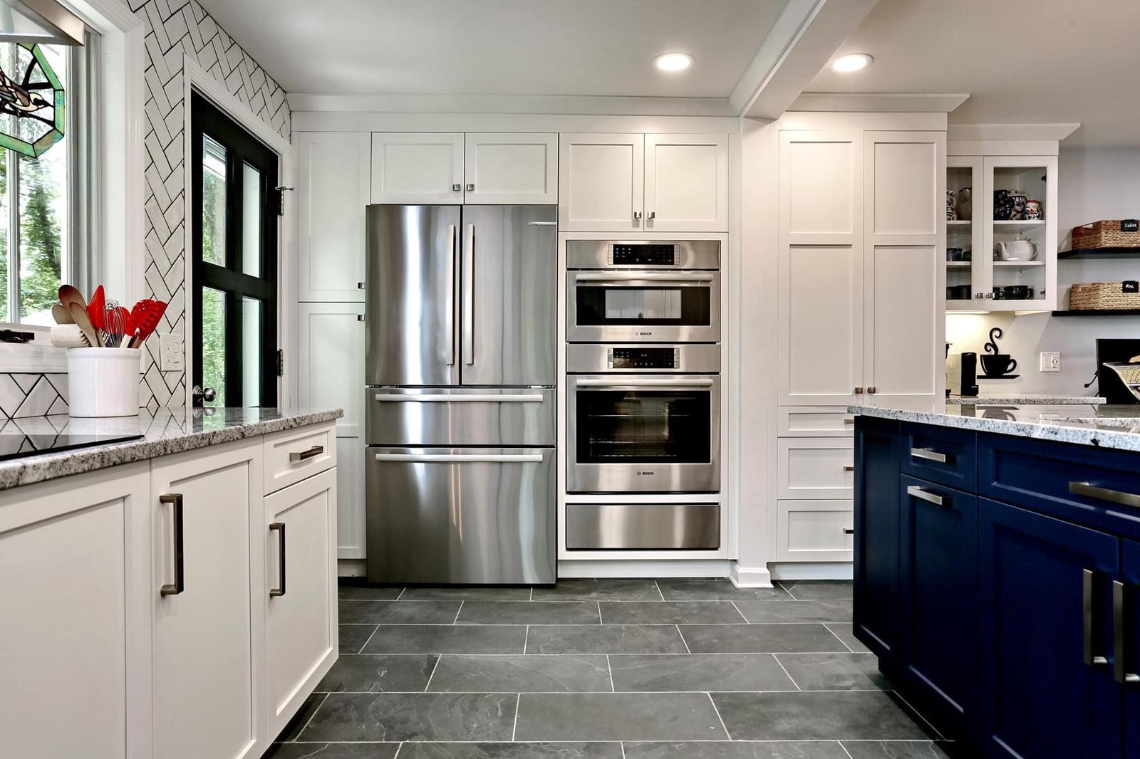 Kitchen appliance wall with built-in refrigerator and double wall ovens beside glass-front cabinets