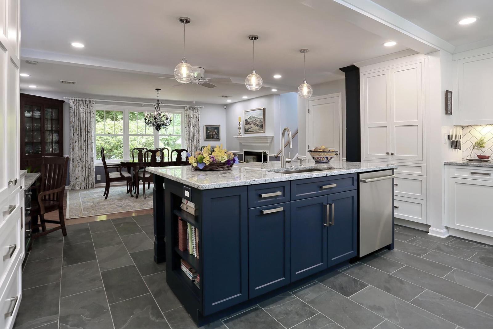 Wide view of the navy island with built-in bookshelf opening into the dining room