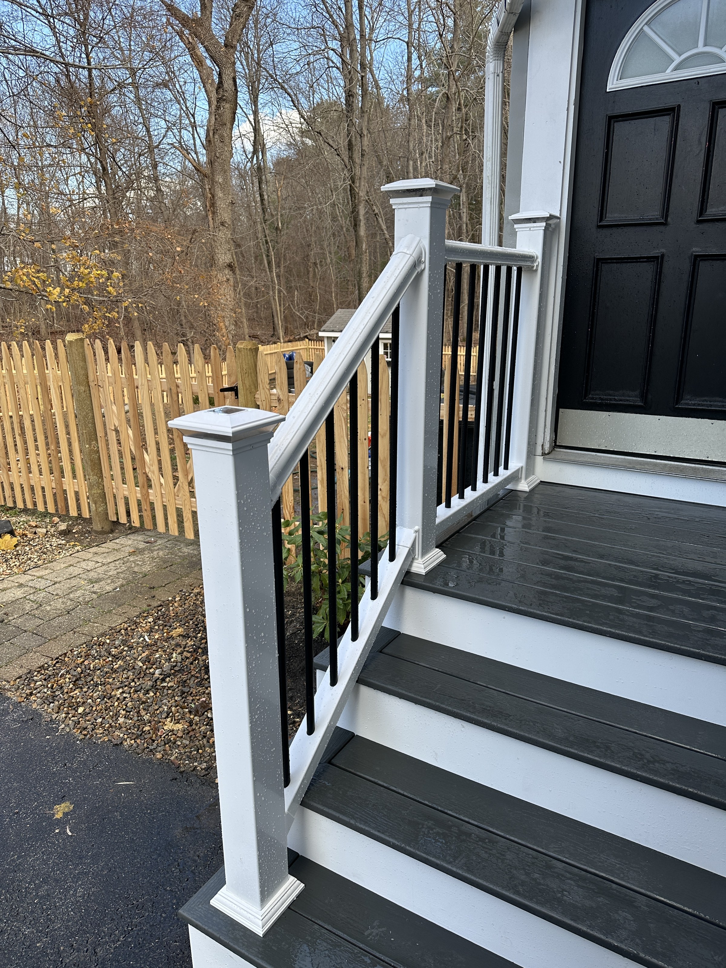Finished entry steps and railing at the top of the stairs, black front door and bare winter trees in the background, Reading