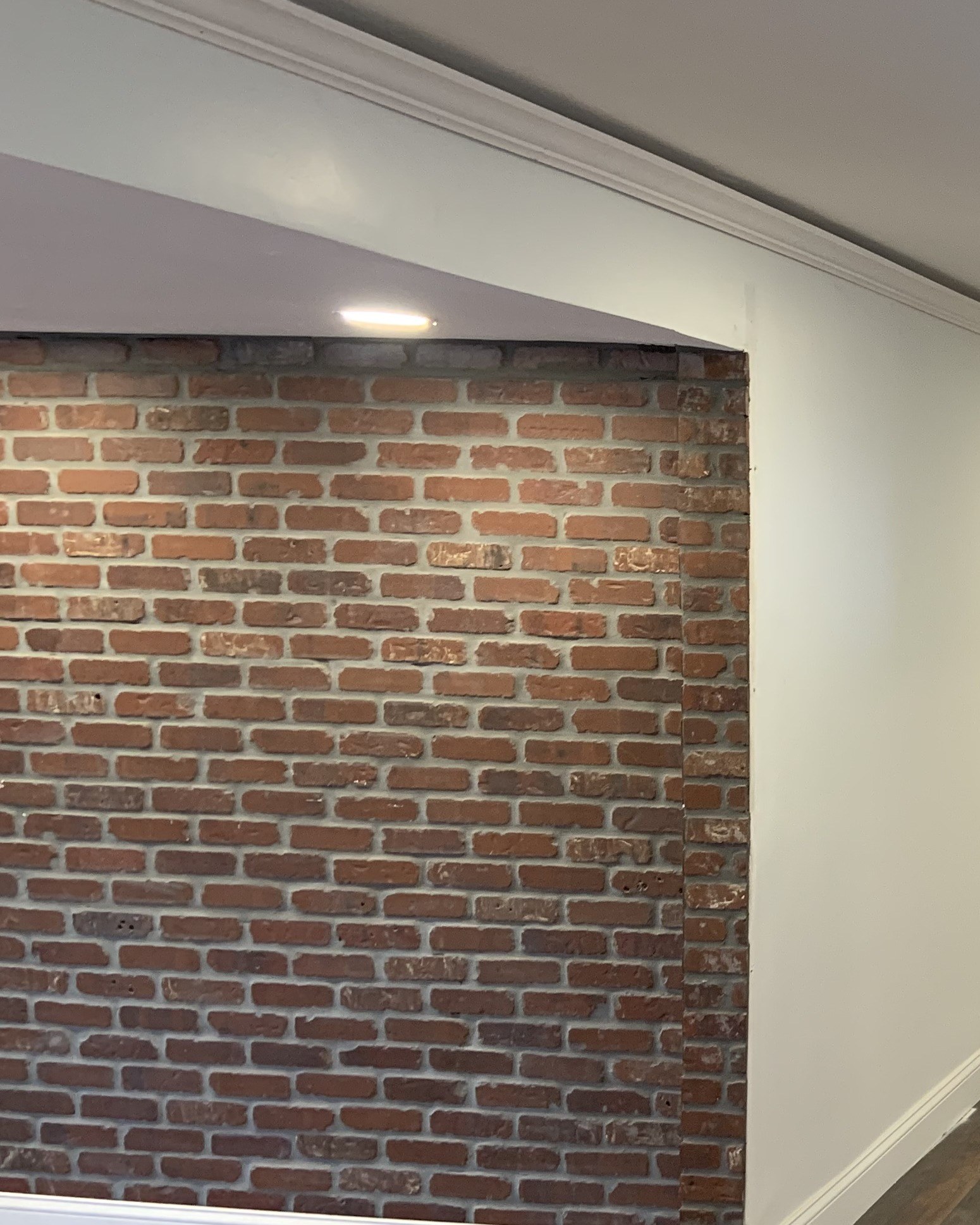 Close detail of the repointed brick accent wall and crown molding, finished basement