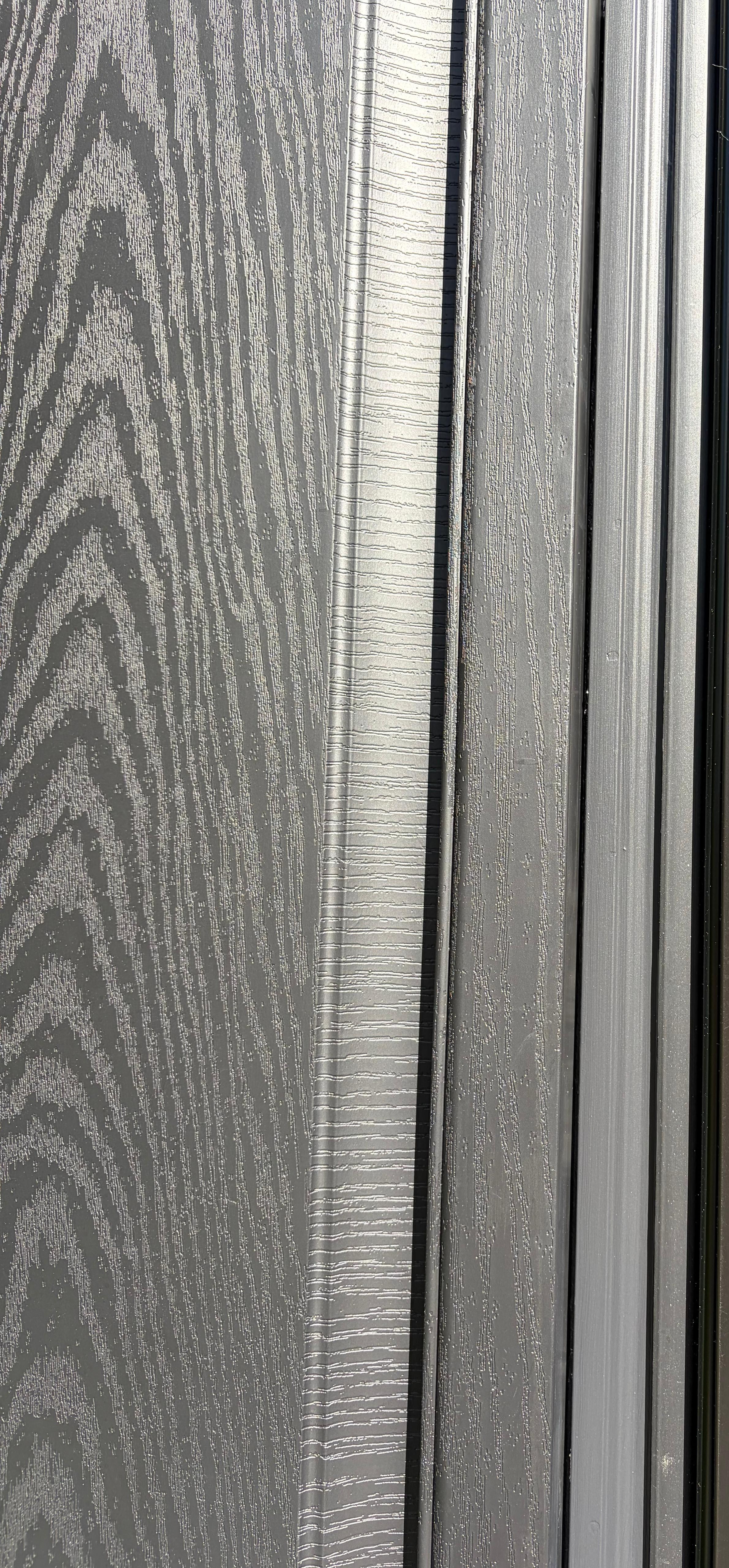 Detail of the woodgrain texture on the black side panel meeting the storm-door frame, Peabody