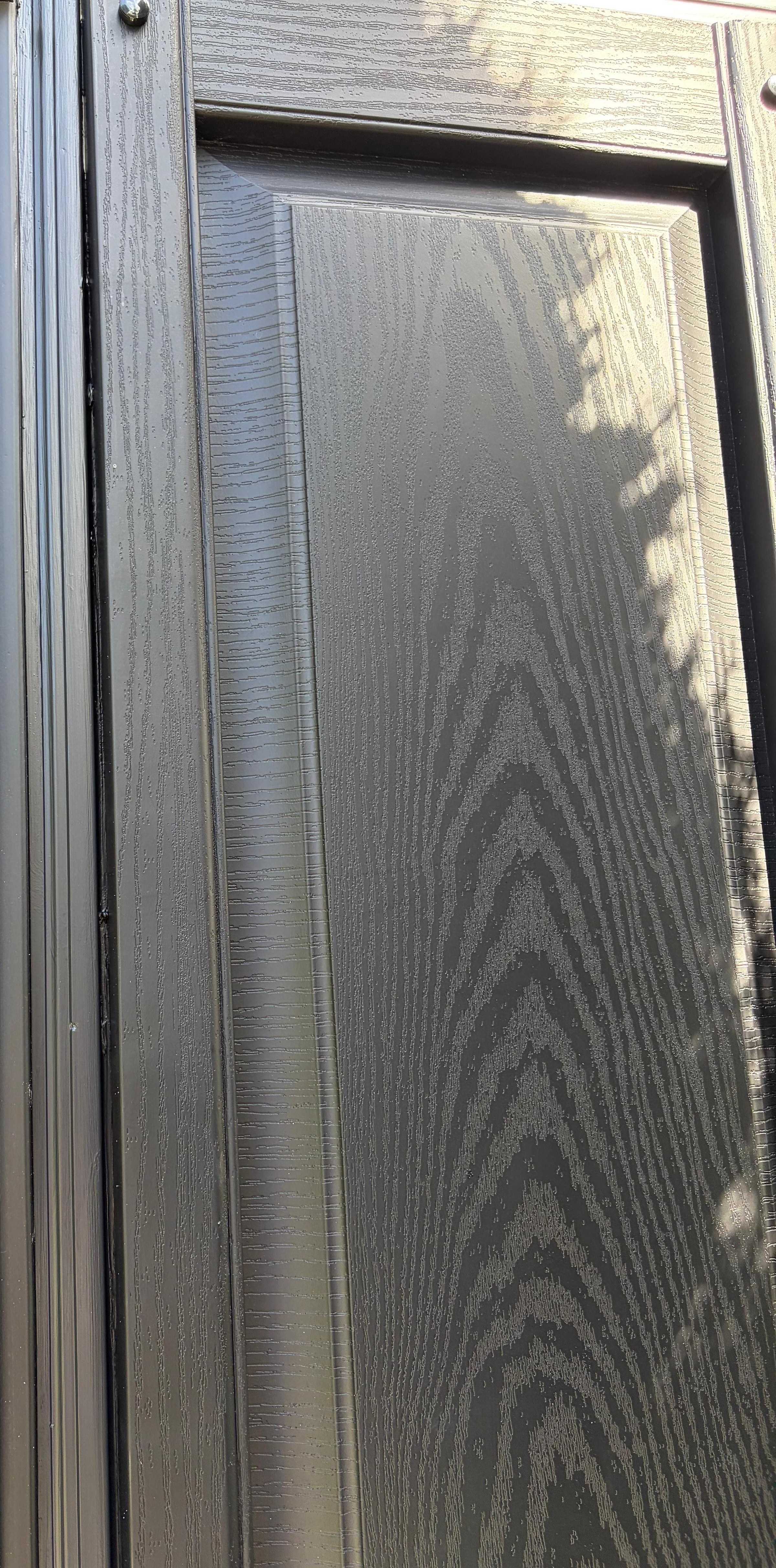 Detail of the black side panel's woodgrain texture with dappled tree shadow, Peabody