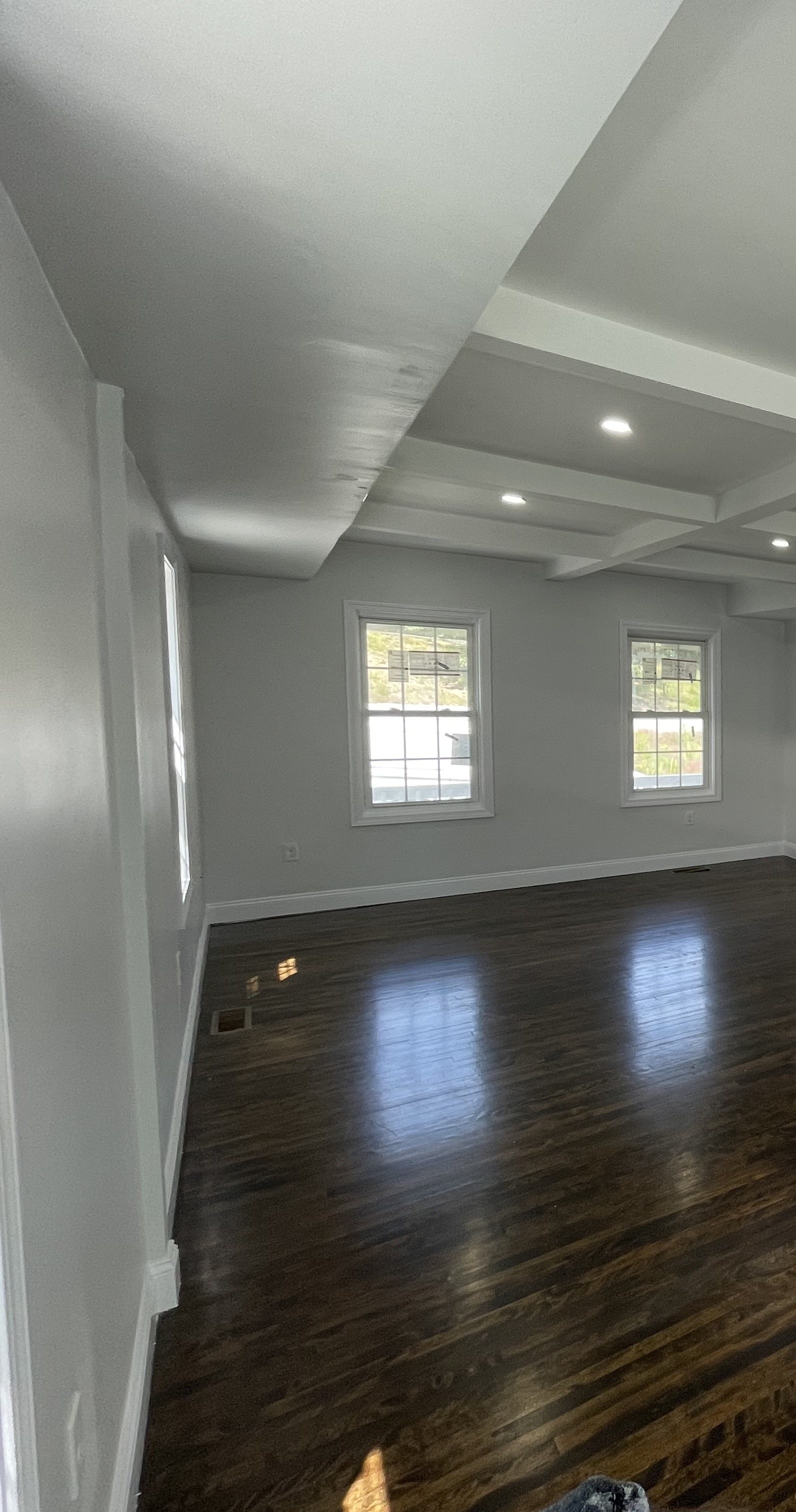Corner view of the same great room's coffered ceiling, beams and window trim
