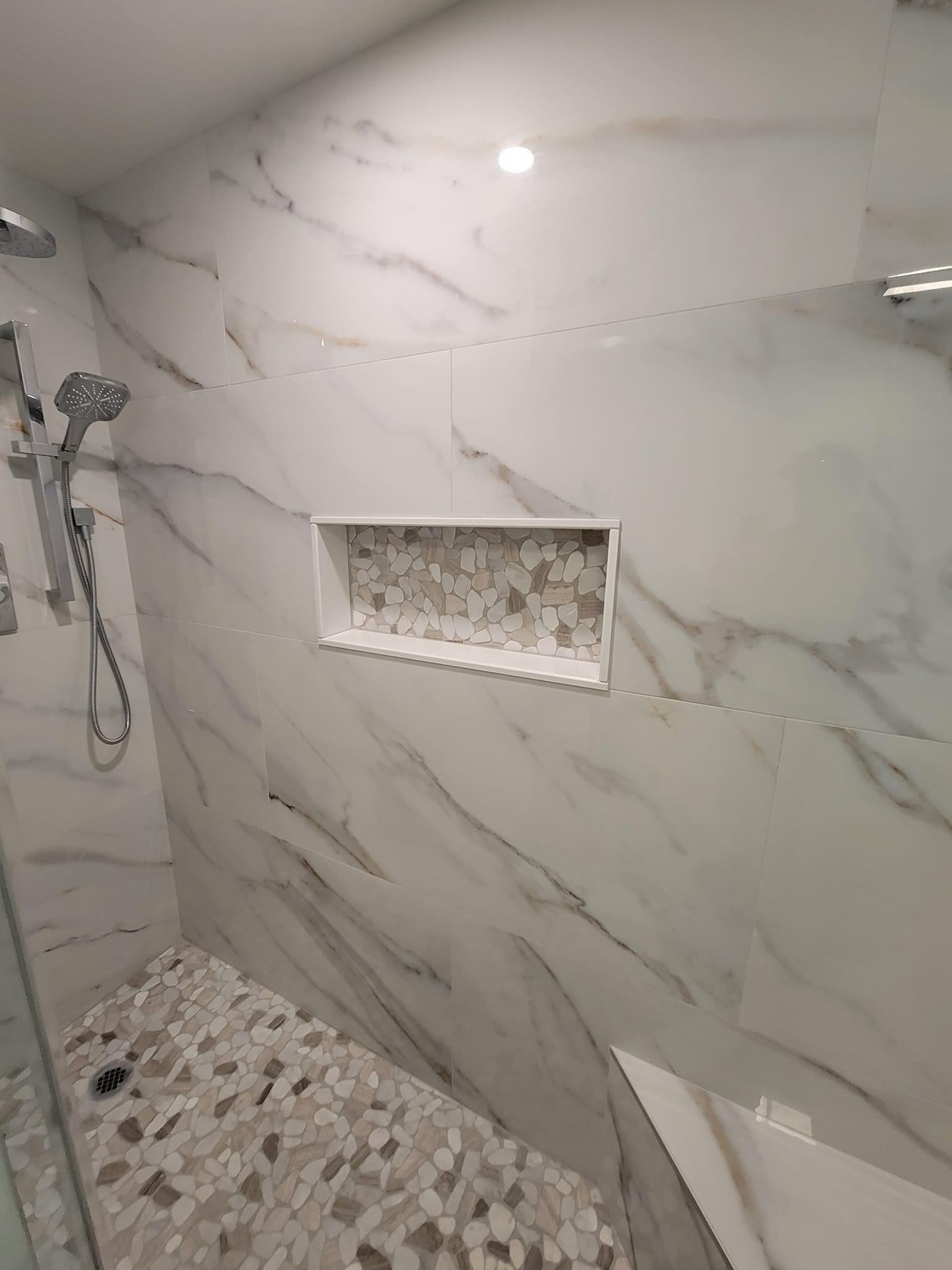 Frameless glass shower with white/gold marble-look tile and a pebble-mosaic niche, Wakefield