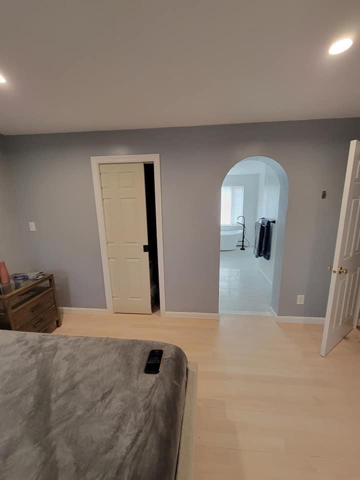Bedroom with an arched doorway opening onto a freestanding-tub bathroom, Melrose