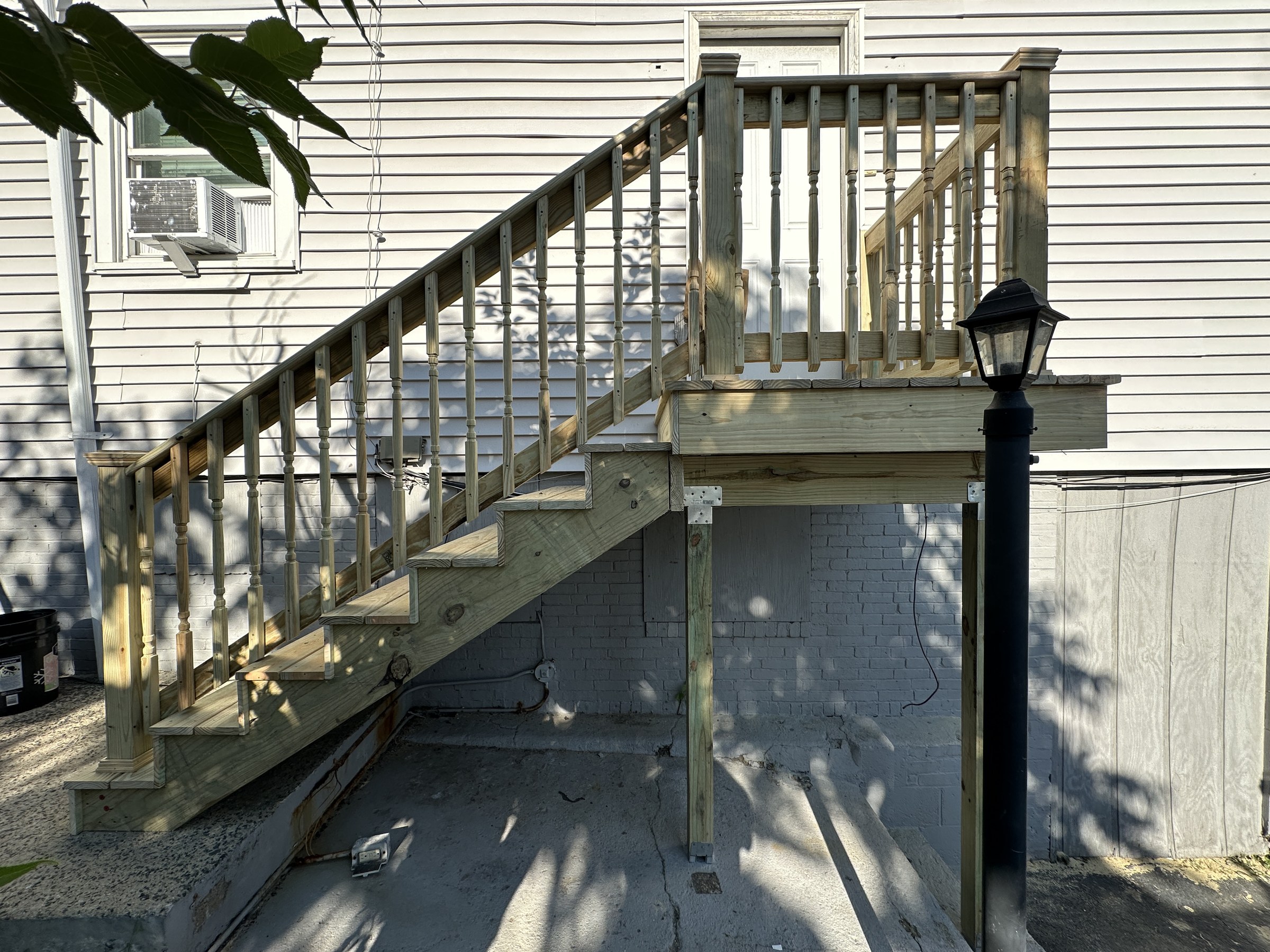 Finished exterior deck staircase with turned wood balusters and capped newel posts