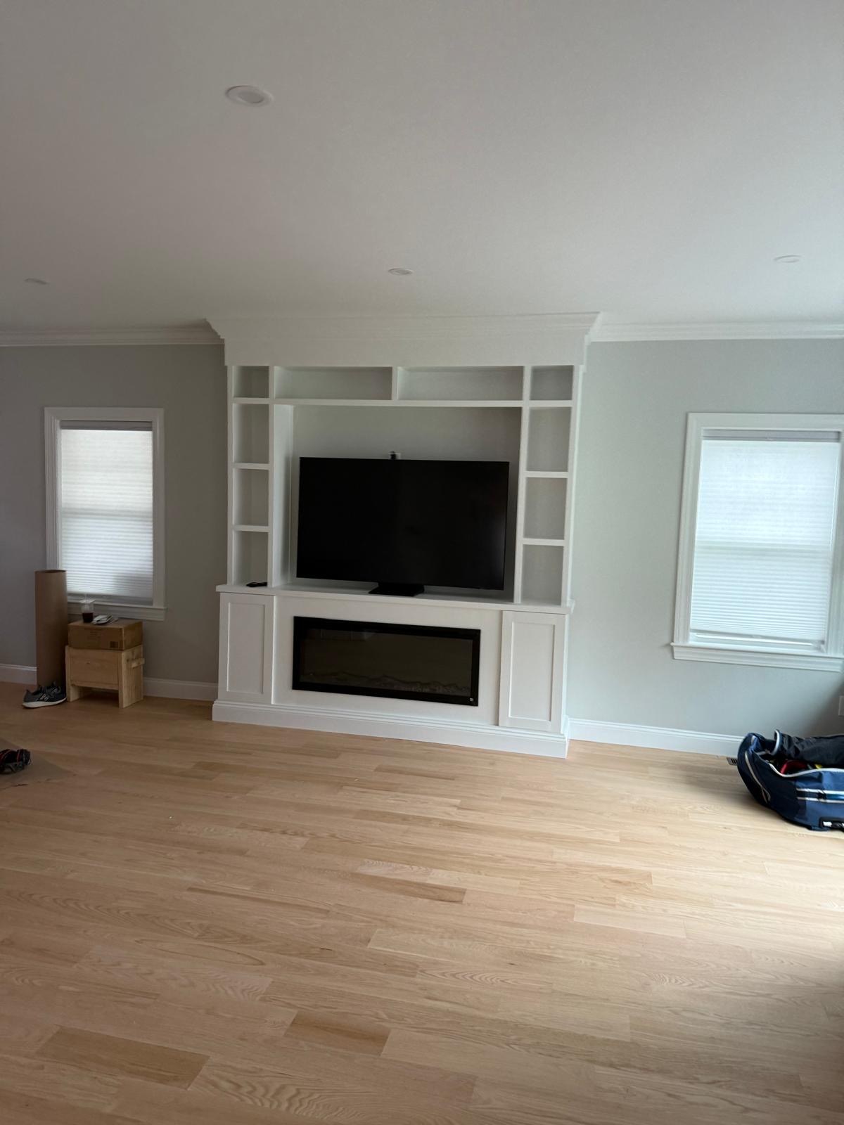 Built-in entertainment center with an electric fireplace niche, open shelving, painted white with crown molding