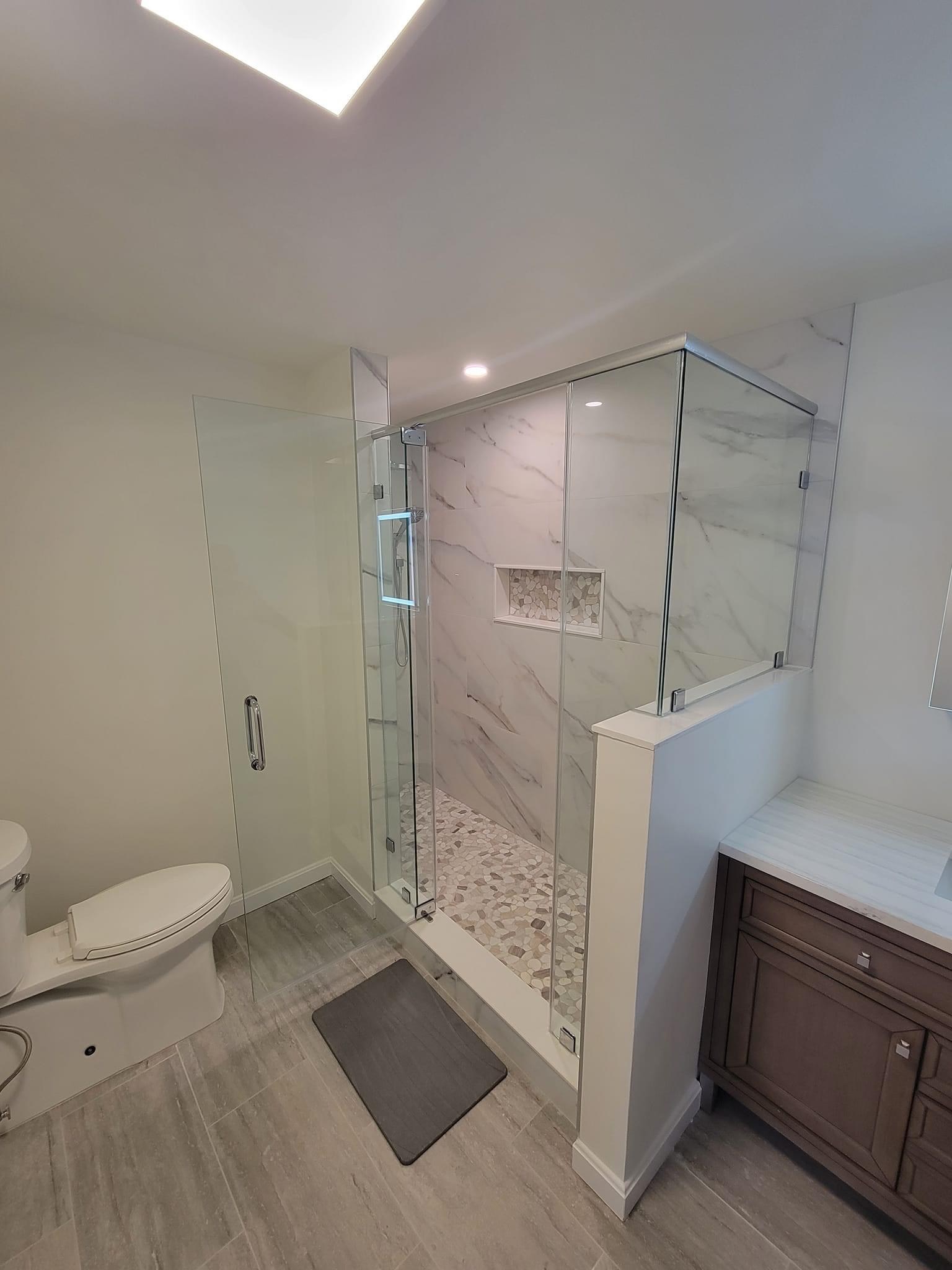 Wide establishing view of a marble-look shower with pebble niche, Reading