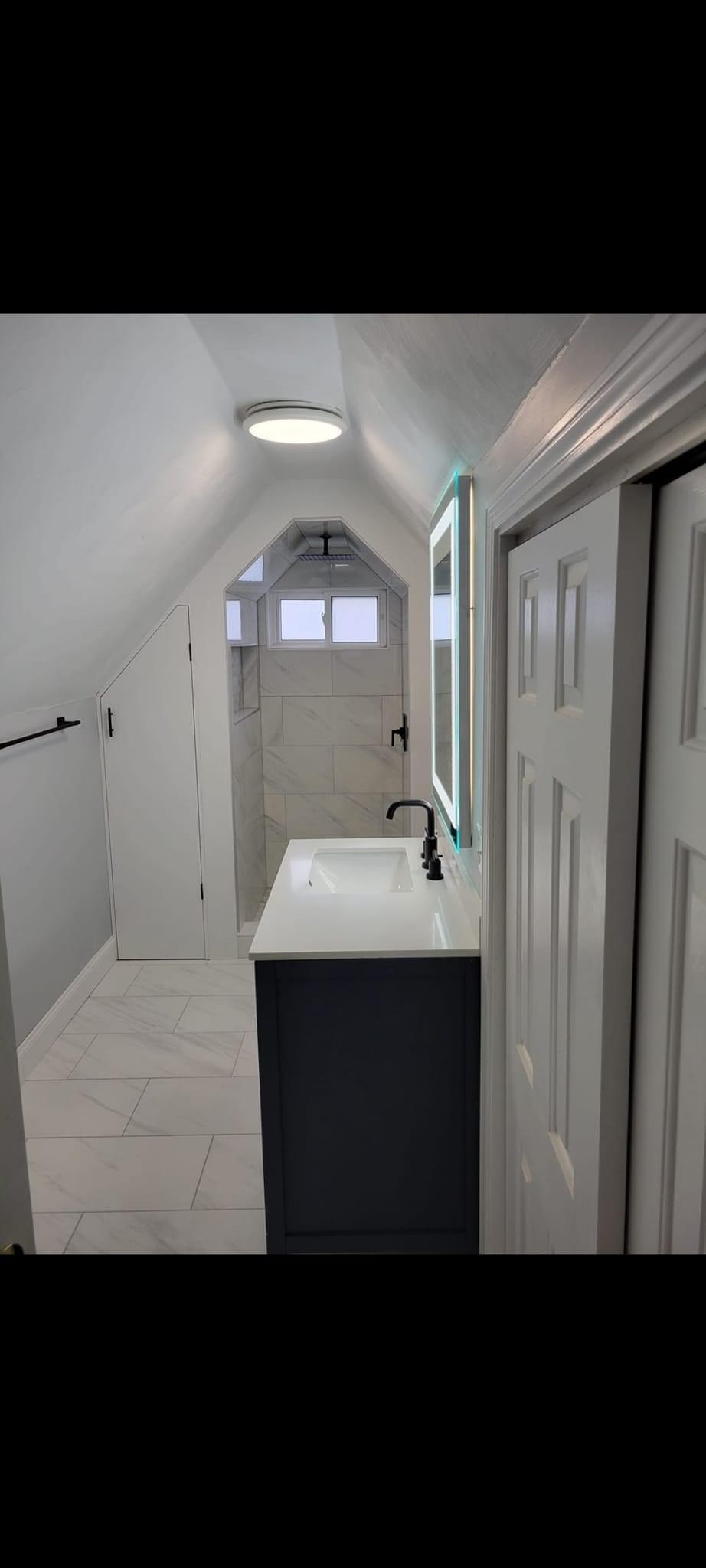 Attic-dormer bathroom with a sloped peaked-ceiling shower nook and navy vanity, Wakefield