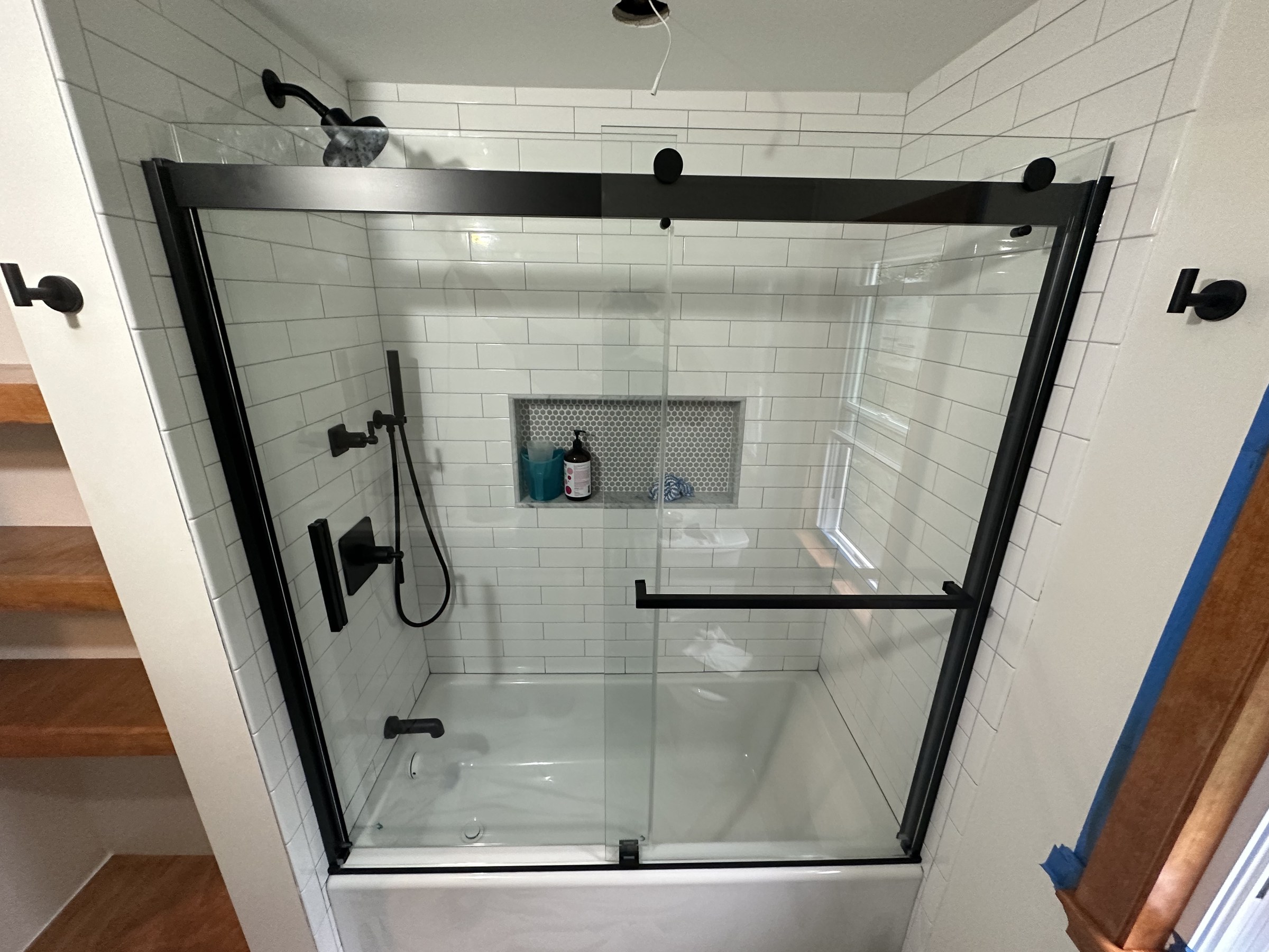 Black-framed sliding-glass tub/shower enclosure with white subway tile, Woburn