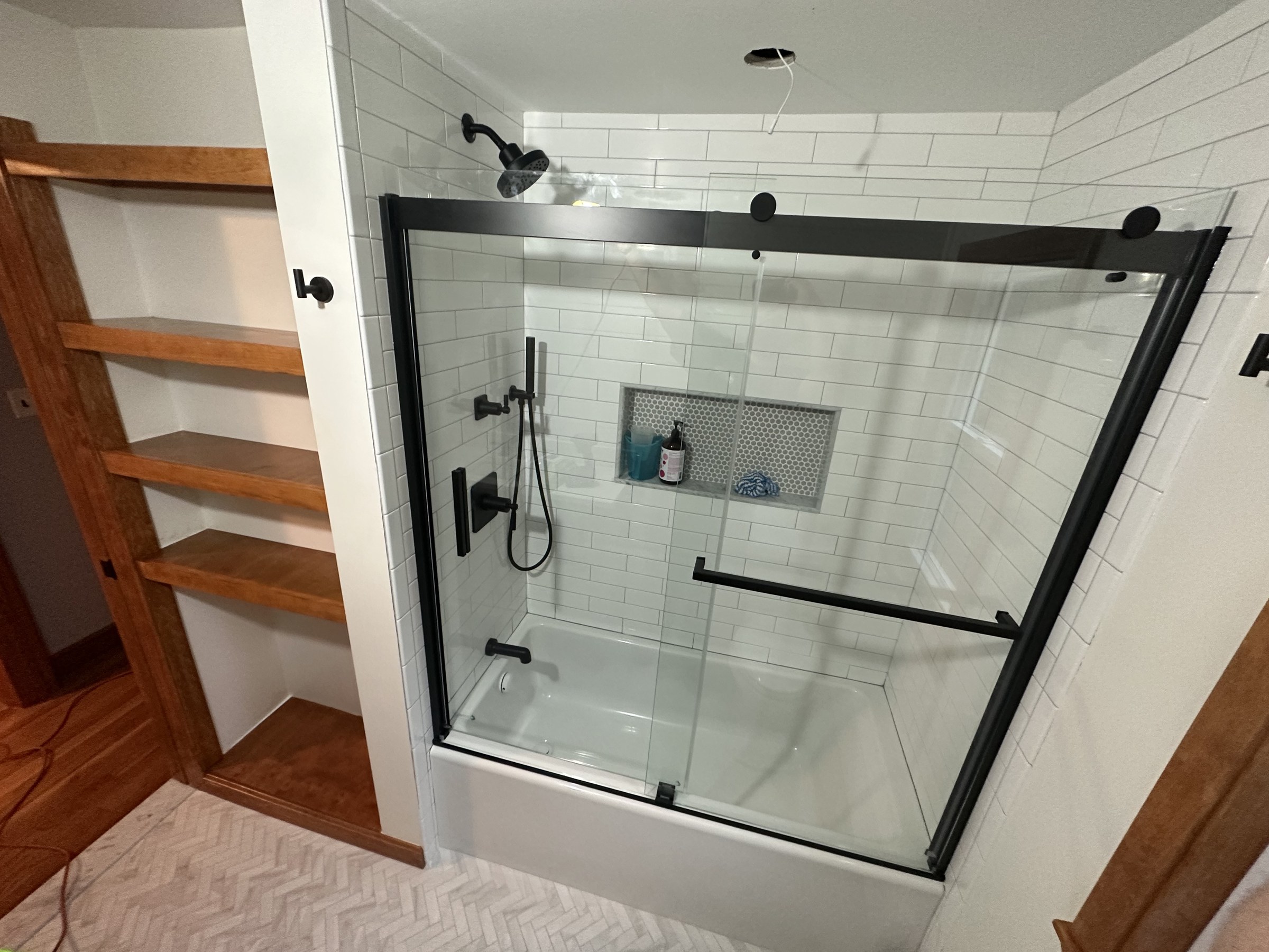 Another angle of the black-framed glass shower with built-in wood corner shelving, Woburn