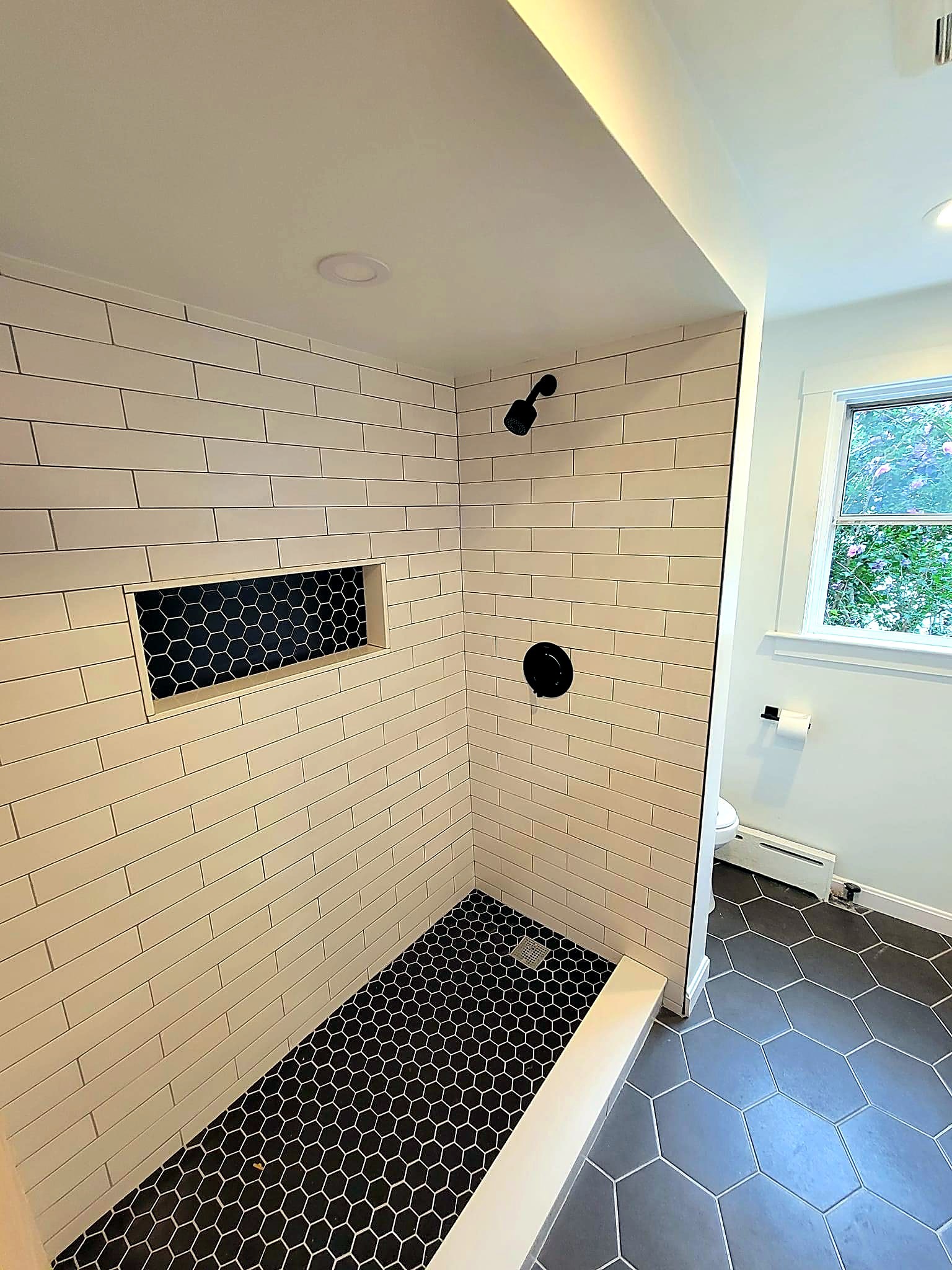 Cream subway-tile shower with a black-hex niche accent and matching floor, Peabody