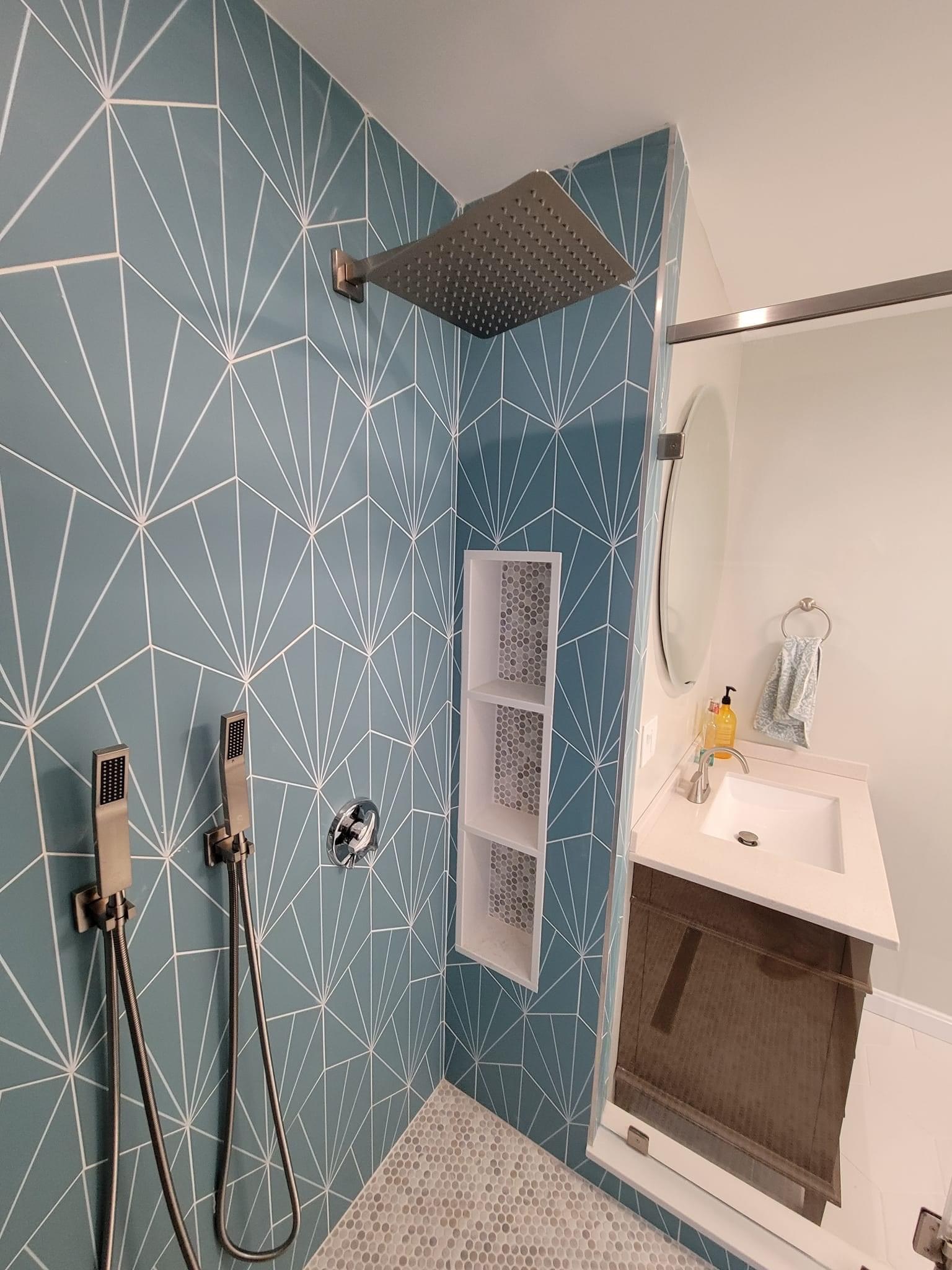 Wider view of the teal fan-tile shower with the vanity and round mirror beyond, North Reading